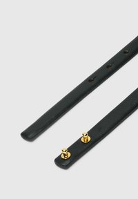 Lanières en cuir noir à texture lisse, ornées de deux clous en métal doré pour la fixation. Design fin, avec des trous régulièrement espacés pour l'ajustement.