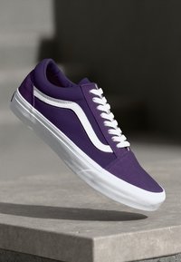 Purple canvas sneaker with white suede sides, padded collar, and white laces. Features a rubber sole and a classic design. Lightweight texture.
