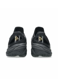 Schwarze Sportschuhe mit einem strukturierten Strick-Obermaterial, glatten synthetischen Akzenten und einer gepolsterten Sohle; mit einem goldenen Logodetail an der Ferse.