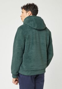 Chaqueta de forro polar verde con capucha, con un acabado texturizado, puños elásticos y un corte relajado. Material suave y costuras sutiles.