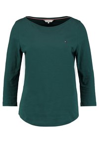 Donkergroene langemouwen shirt van katoen, met een bootnek, een gebogen zoom en een klein logo detail op de borst.