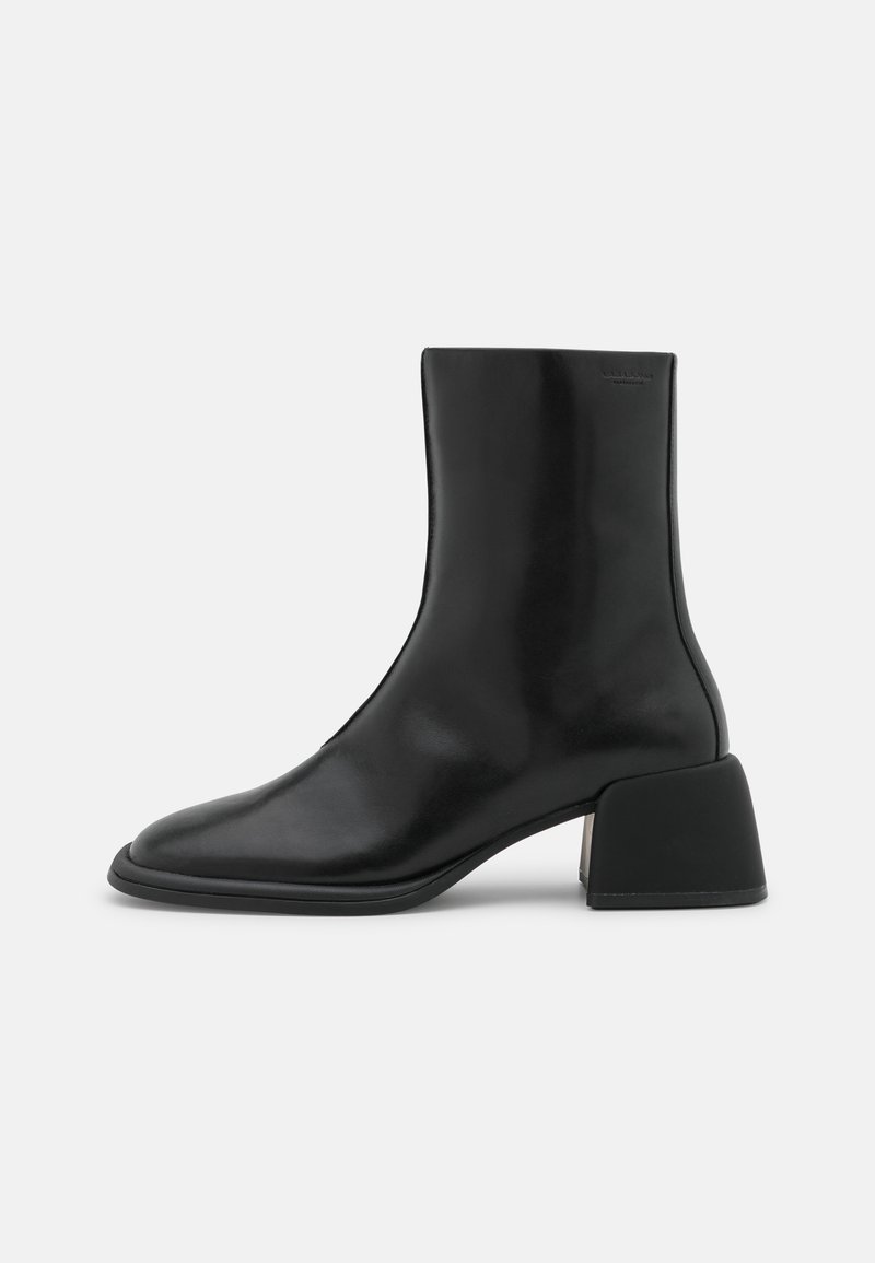 Bottine en cuir noir avec bout carré et talon bloc, design minimaliste, finition lisse et hauteur mi-mollet.