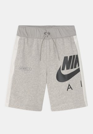 Pantalones cortos Nike Air de color gris claro con cintura elástica, cordón ajustable, paneles laterales de malla blanca y un gran logotipo negro de Nike en forma de swoosh en la pierna derecha.