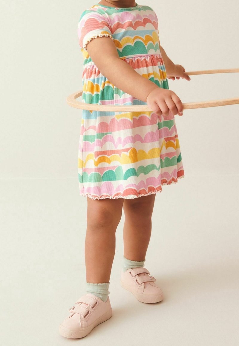 Robe colorée avec un motif festonné en rose, vert, jaune et bleu, dotée de manches courtes et d'un ourlet volé. Baskets roses avec des brides en Velcro.