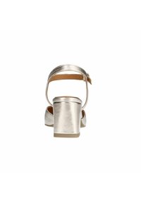 Sandale argentée à talon haut avec un talon bloc, une bride cheville et une finition métallique lisse. Design à dos ouvert avec une semelle légèrement rembourrée.