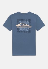 Mėlynas trumpų rankovių marškinėliai, puošiami dideliu grafikiniu spausdinimu su bangomis ir "Quiksilver" logotipu šviesiai smėlio ir juodais akcentais. Lygus paviršius.
