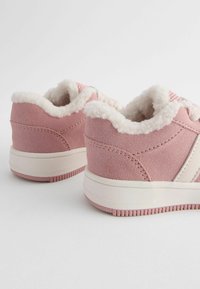 Rosa mockaläder sneakers med vit pälskant och detaljer. Har en mjuk yta, gummisulor och sömdetaljer vid hälen och sidorna.