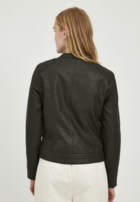 Giubbotto in pelle nera con accenti a coste sulle spalle, vestibilità su misura e texture liscia. Design leggermente corto con orlo dritto.