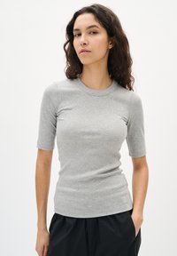 Top gri cu dungi, cu manșete scurte și decolteu rotund, având o siluetă ajustată și o textură subtilă. Purtați-l cu pantaloni negri, lejeri.