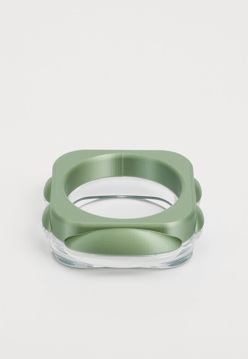 Kvadrataanne anum, millel on matt roheline metallkate, ümarad nurgad ja läbipaistev alumine osa. Sile tekstuur ja stiilne disain.