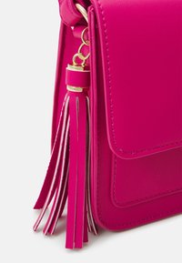 Horkorůžová syntetická kožená taška s klopovým zavíráním, zlatým kováním a mnohovrstvým třásním v podobných odstínech.