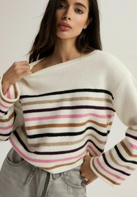 Sweter w paski w kolorze kremowym z poziomymi paskami w kolorach różowym, brązowym, czarnym i fioletowym. Miękka tekstura, szeroki dekolt i długie rękawy.