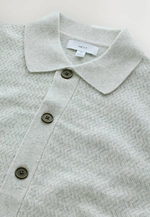 Hellgraue Strickjacke mit Fischgrätenmuster, Knopfverschluss und einer weichen, strukturierten Oberfläche. Verfügt über einen Kragen und dunkle Knöpfe.
