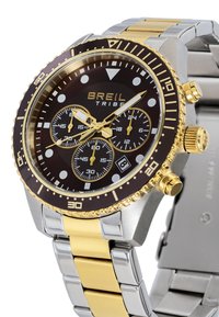 Montre chronographe Breil Tribe avec un cadran noir, un bracelet en métal doré et argenté, des index lumineux et un affichage de la date à 6 heures.