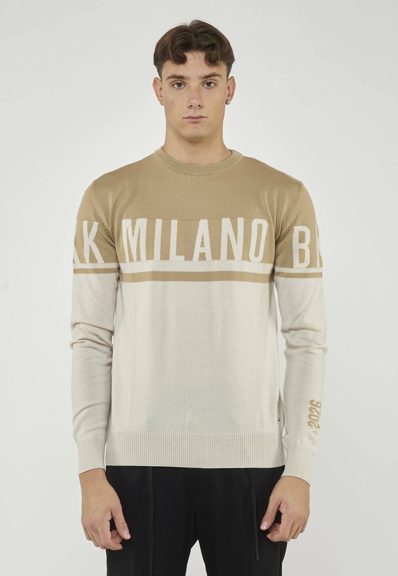 Maglione a maglia crema e beige, con audace scritta "MILANO", collo rotondo, maniche lunghe e polsini a costine. Accentuato con dettagli "2026".