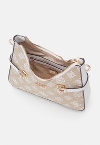 Sac à main beige avec motif logo blanc, métal doré et fermeture éclair. Intérieur comprenant une poche zippée et une étiquette de marque. Design structuré.