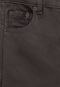 Tissu marron texturé de jeans en denim avec une poche avant ornée d'accents métalliques et des coutures contrastantes le long des coutures.