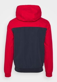 Leichte Jacke in Rot und Marineblau mit Farbblockierung, Kapuze, elastischen Bündchen und unterem Saum. Glatte Textur mit modernem athletischem Design.