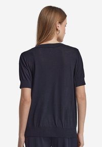 Marinblå stickad tröja med korta ärmar, rund halsringning och ribbad nederkant. Materialet verkar mjukt med en lätt, något texturerad yta.