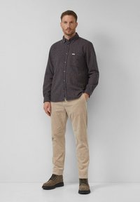 Karierter Button-Down-Hemd in Dunkelblau und Rot, kombiniert mit beigen Cordhosen und braunen Schnürstiefeln. Schlichtes Design, taillierte Passform.