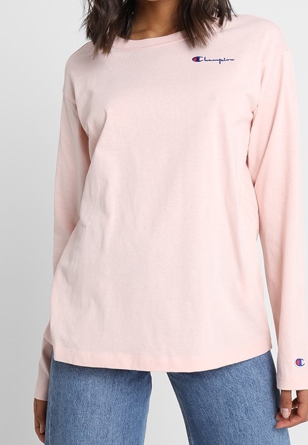 Lyserød langærmet t-shirt lavet af bomuld. Har et lille blåt logo på brystet og et logo på manchetten. Casual pasform.