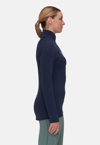 Top a maniche lunghe e collo alto in blu navy con un design aderente e tessuto textured. Presenta un piccolo logo sul petto e cuciture lisce.