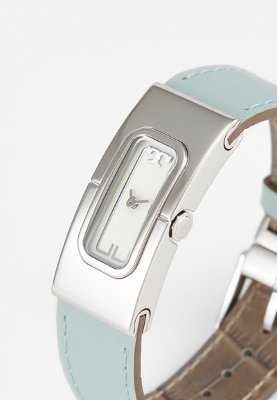 Silberne rechteckige Uhr mit schmalem weißem Zifferblatt, minimalistischen Zeigern und hellblauem Lederarmband mit sichtbarer Naht.