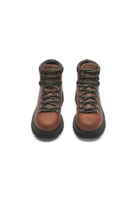 Scarpe da trekking in pelle marrone con collarino imbottito, lacci verdi, occhielli metallici e suola robusta in gomma nera.