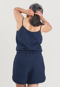 Marineblauwe mouwloze top met dunne bandjes, gecombineerd met shorts, in een textuurstof en met een elastische tailleband. Achteraanzicht toont een relaxte pasvorm.
