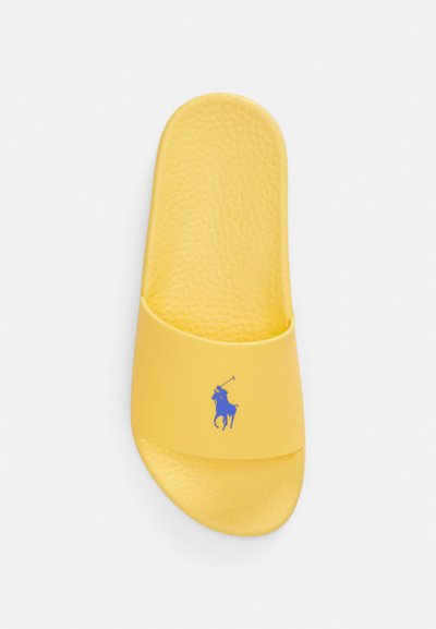 Κίτρινο σανδάλι με λουράκι με απαλό υφή, με μπλε λογότυπο αλόγου και αναβάτη. Στρογγυλεμένη μύτη και ανοιχτός σχεδιασμός για καλύτερο αερισμό.
