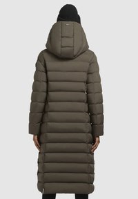 Olu kokā zaļš, garš pūka mētelis ar vertikāliem izšuvumiem, regulējama kapuce un vidukļa garums. Iespējas melna adīta cepure.