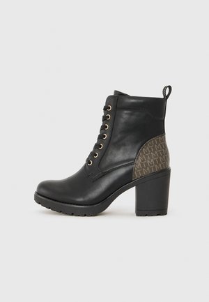 Bottine noire en cuir avec un design de lacets dorés, présentant un panneau latéral texturé à motifs bruns et un talon noir épais.