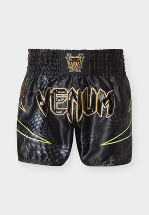 Črne Muay Thai kratke hlače z zlatim in rumenim vzorcem kačjih lusk, elastičnim pasom in napisom "VENUM" v odebeljenih črkah na sprednji strani.