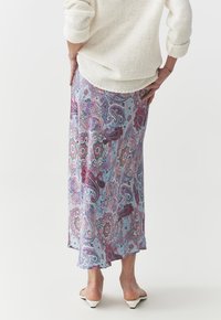 Longue jupe paisley dans des tons de bleu, rose et violet. Le tissu est léger avec un design fluide, présentant des motifs floraux complexes.