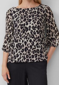 Blouse à imprimé léopard avec manches trois-quarts, tissu plissé, encolure arrondie et coupe décontractée, associée à un pantalon noir.