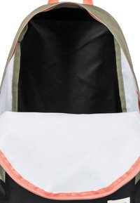 Czarny plecak z jasnoszarym wnętrzem. Posiada oliwkowozielony zewnętrzny kolor oraz koralowe wykończenie. Otwór jest szeroki, co umożliwia łatwy dostęp do zawartości.