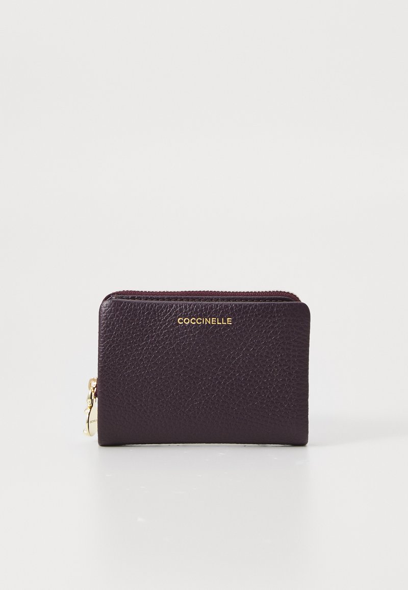 Portafoglio compatto in pelle viola scuro con zip dorata e logo "Coccinelle" impresso in oro al centro davanti.