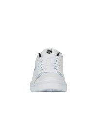 White sneakers featuring a smooth leather upper, lace closure, black accents, and a round logo on the tongue. Flat rubber sole.