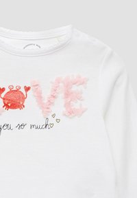 Camicia bianca a maniche lunghe con lettere rosa "LOVE" testurizzate, un grafico di granchio rosso e la scritta nera stampata "you so much" con cuori dorati.