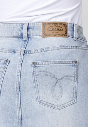 Light blue denim jeans featuring a leather patch, intricate stitching on the back pockets, and a classic five-pocket design.