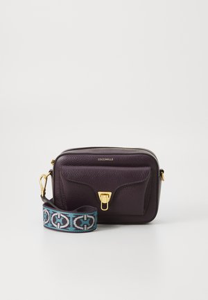Lila Leder Umschlagtasche mit einer Fronttasche, goldenen Beschlägen und einem gemusterten türkisfarbenen Riemen mit einem schwarzen Design.