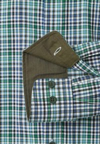 Geblokt shirt met een mix van blauwe, groene en witte patronen, met een donkergroene kraag en twee donkergroene knopen op de manchet.