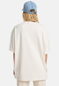 Cremefarvet oversized t-shirt med korte ærmer, lavet af blødt bomuldsstof, med rund halsudskæring og en lille detalje på ryggen.