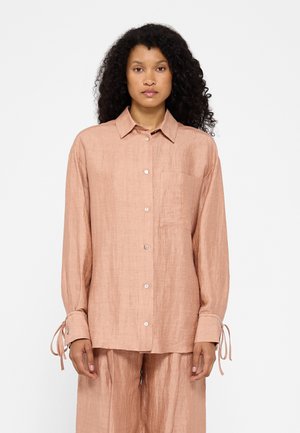 Hemd aus leichtem rosa Leinen mit Knopfleiste, Kragen, Brusttasche und langen Ärmeln, die an den Handgelenken gebunden sind. Glattes, leicht strukturiertes Material.