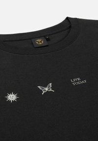 Zwarte sweatshirt van katoen met witte geborduurde ontwerpen van een zon en een vlinder. Tekst zegt "LEEF VANDAAG" in een eenvoudig lettertype.