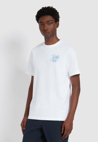 Witte katoenen t-shirt met een ronde hals en korte mouwen, met een blauw grafisch ontwerp op het linkerborstgedeelte.