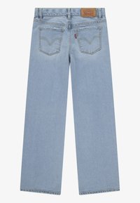 Světlé modré džínové kalhoty s rovným střihem nohavic, vybavené dvěma zadními kapsami a koženou štítkem v pase. Bez viditelných opotřebení.