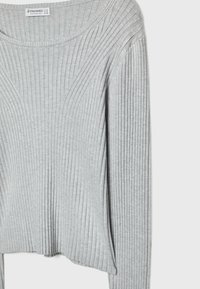 Grauer gerippter Pullover mit langen Ärmeln und rundem Ausschnitt. Der Stoff zeigt vertikale Streifen und einen leicht gekürzten Saum. Weiche Textur.