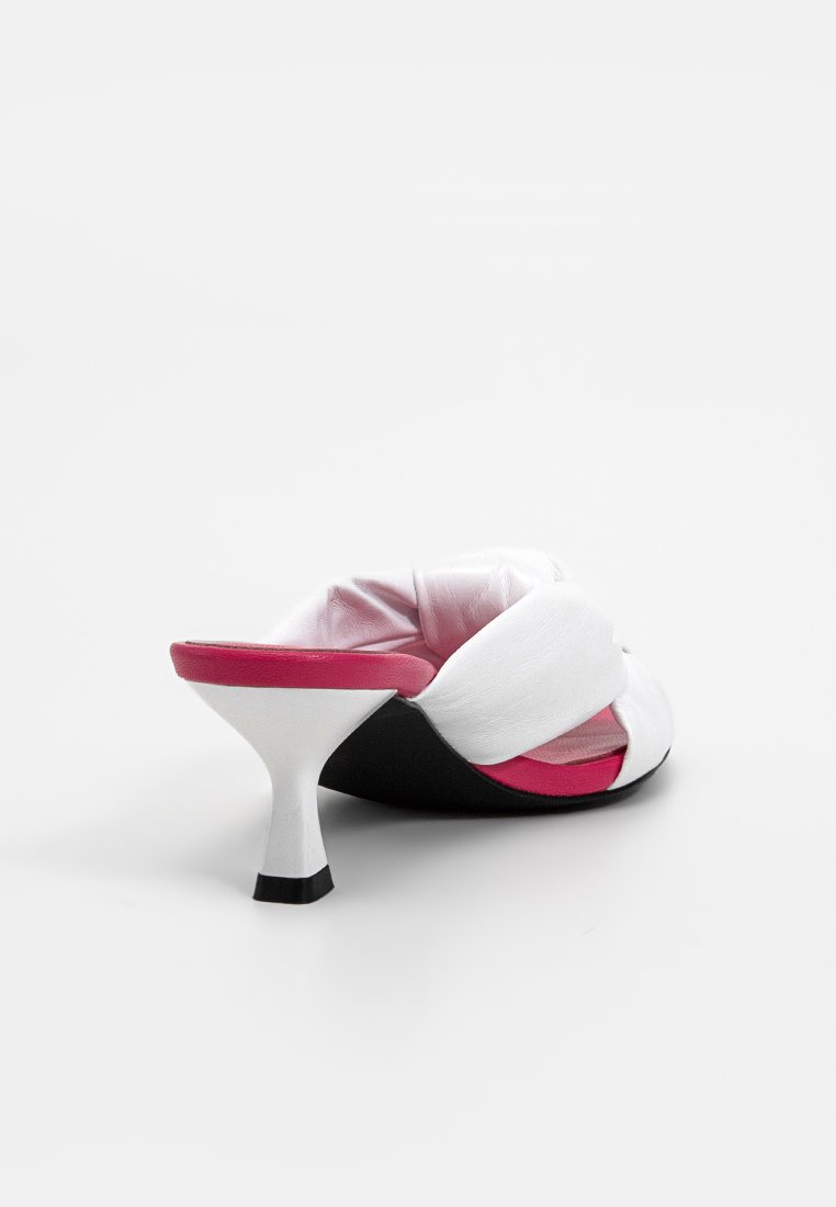 Weißer und schwarzer Rutschsandal mit einem gewundenen Riemendesign, kontrastierendem pinkfarbenem Innenfutter und einem zugespitzten weißen Absatz mit schwarzem Fußteil.