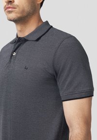 Męska szara koszulka polo z teksturowanej tkaniny, kontrastowym, paskowanym kołnierzykiem, trzema guzikami z przodu oraz małym logo na piersi.